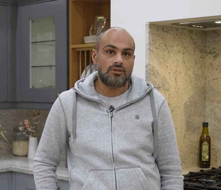 Testimonial video still of a customer speaking in their kitchen after an Ivory Fantasy Granite worktop installation by Mayfair Worktops.