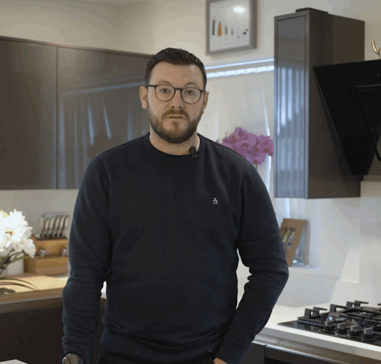David standing in his kitchen beside an Imperial White Quartz worktop with a built-in gas hob