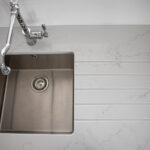 Top down view of Statuario Bianco Porcelain worktops with stainless steel sink and subtle grey veining