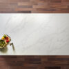 White Calacatta Quartz slab displayed on a wooden surface with food styling and grey veining
