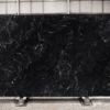 Midnight Black Quartz full slab on a factory stand showing swirling black stone-effect pattern with smoky lighter movement