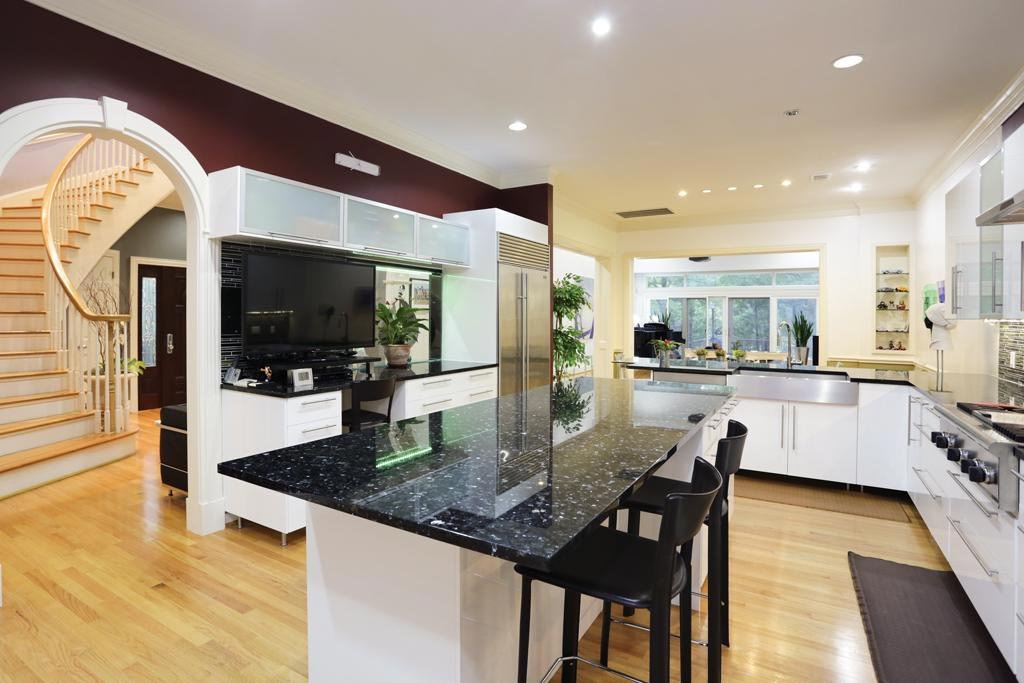 Modern open plan kitchen with Emerald Pearl Granite worktops on an island, showing the polished dark surface with subtle green flecks and bar seating.