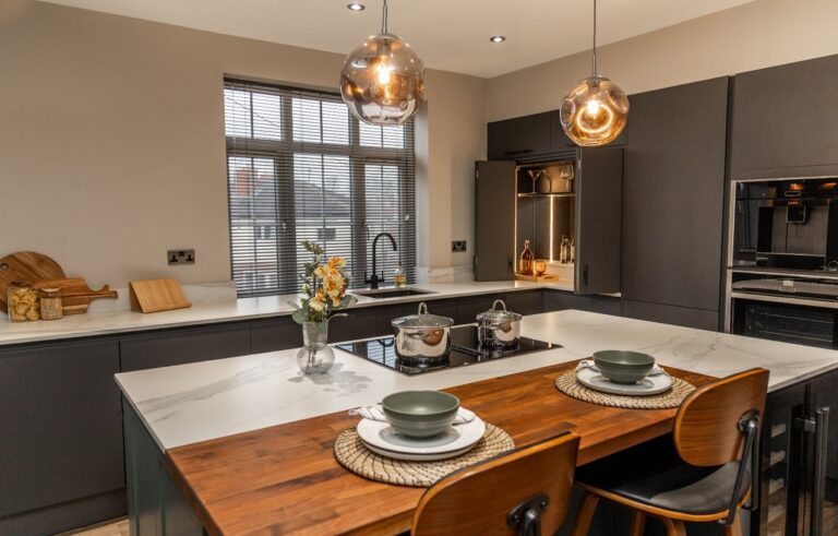 Volakas White Porcelain island worktop with subtle grey veining, shown with pendant lighting and dining place settings.