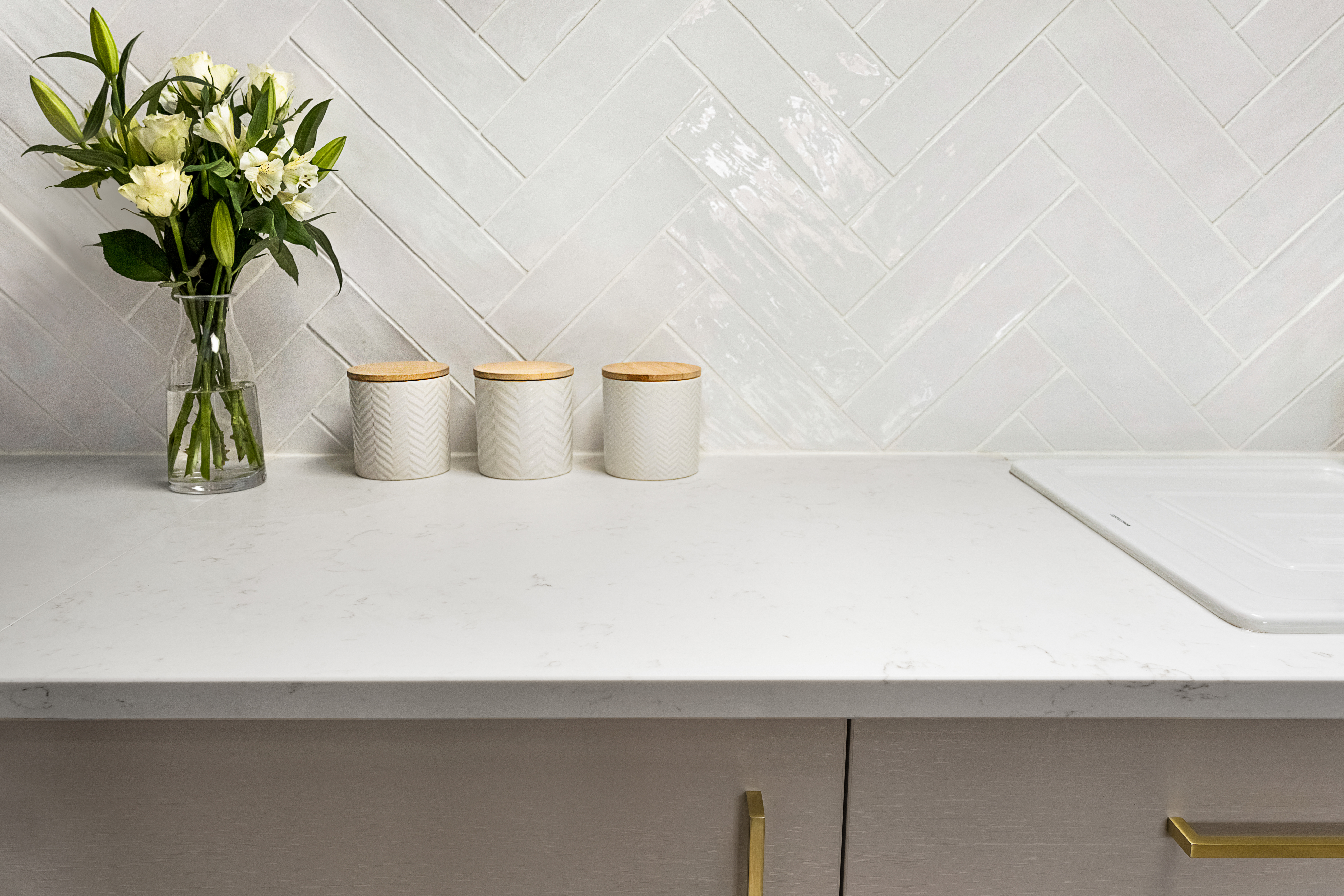 Carrara Quartz worktop with decorative jars and herringbone tiled splashback