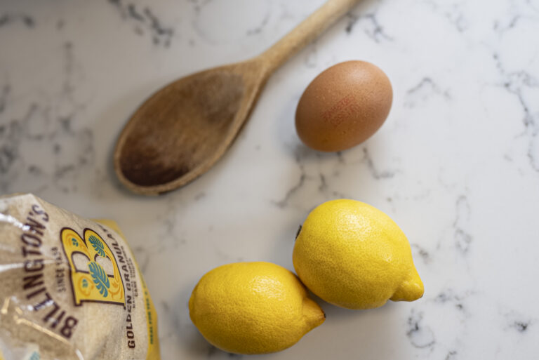 Arabescato Quartz worktop close-up with lemons and a wooden spoon showing grey veining on a white surface