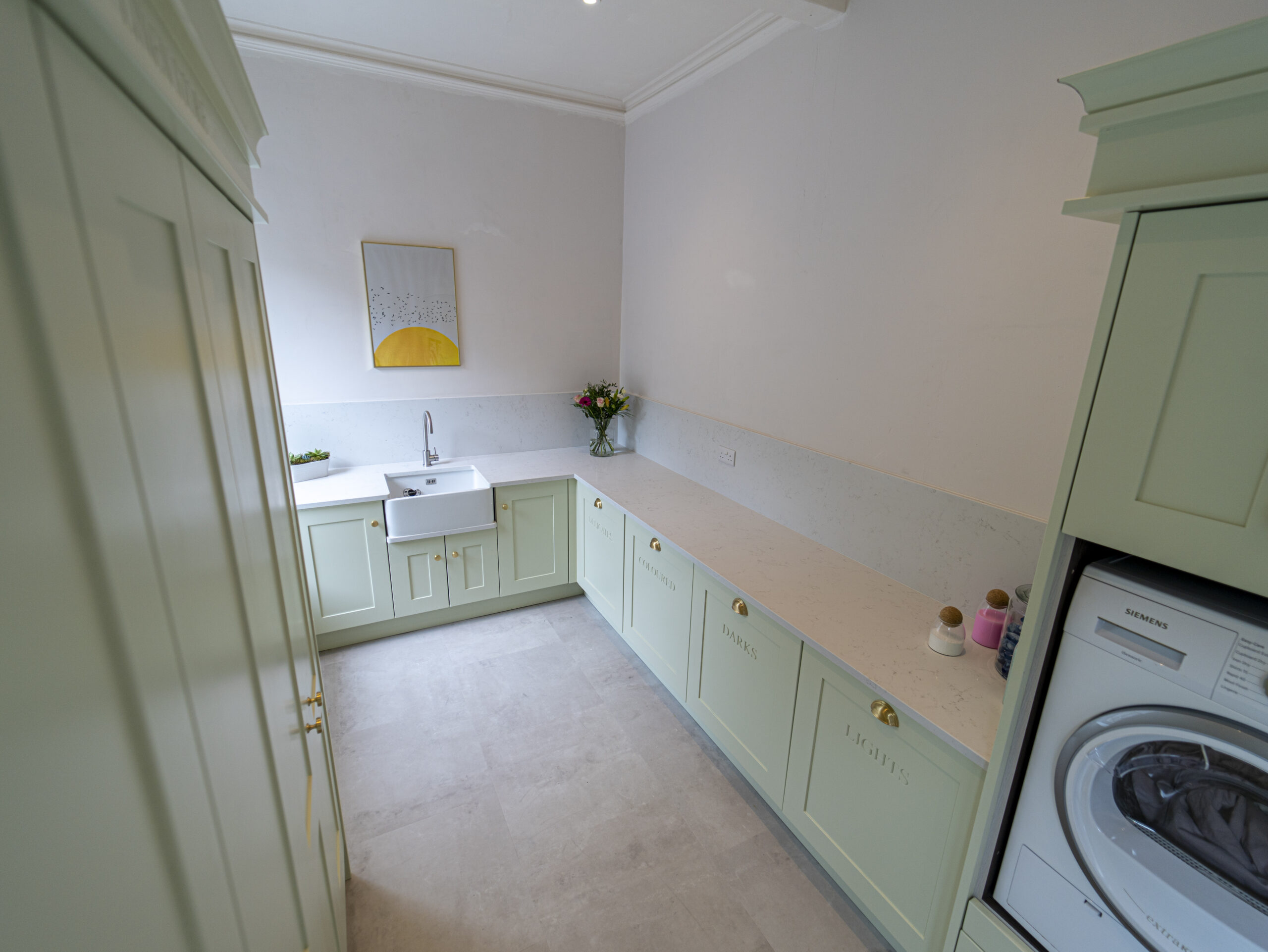 Carrara Quartz worktops in a clean, modern laundry room with mint green cabinets