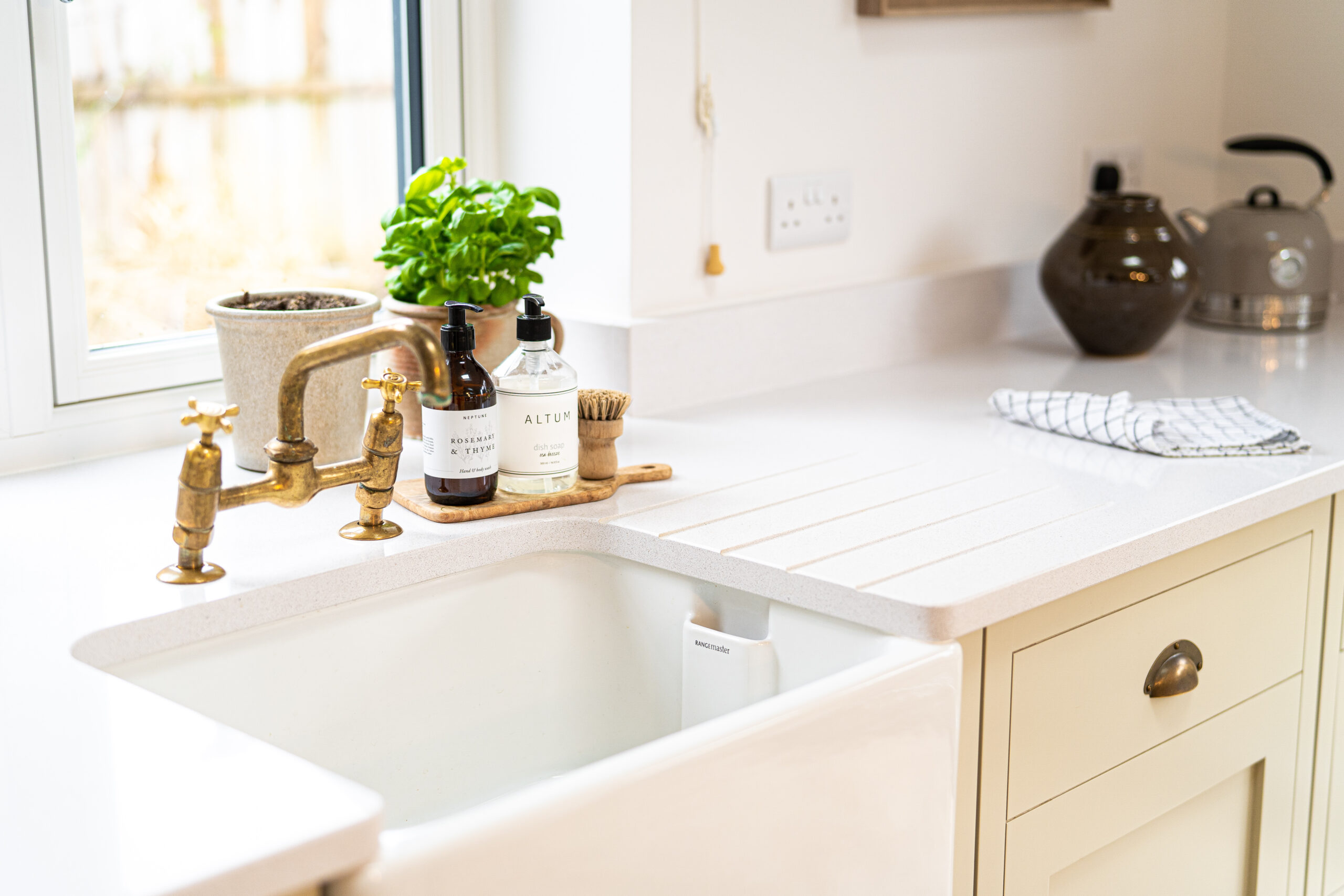 Ice White Quartz sink area with drainer grooves and brass tap in a light kitchen setting