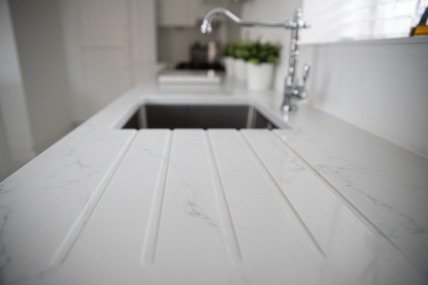 Statuario Bianco Porcelain drainer grooves beside sink showing subtle grey veining