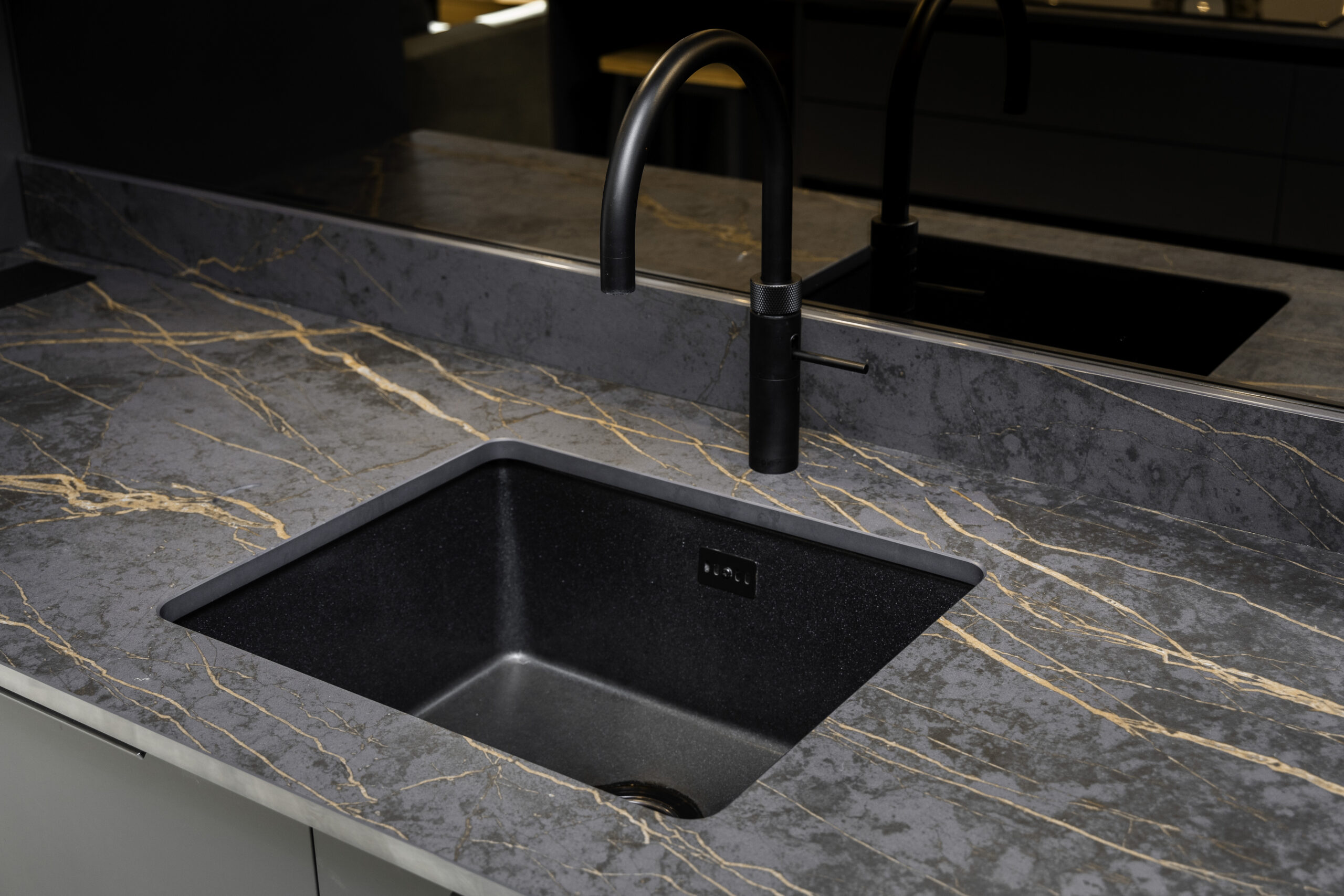 Laurent Porcelain worktop close-up around an undermount sink with a black tap, showing the veining detail across the surface.