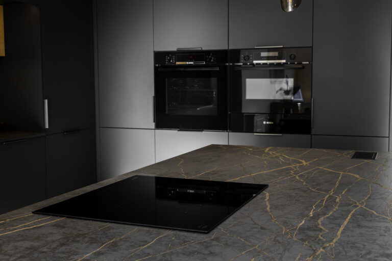 Laurent Porcelain island worktop with an inset induction hob, shown in a modern kitchen with tall units and built-in ovens.