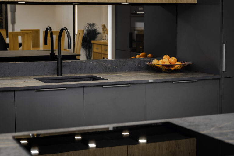 Angled view of Laurent Porcelain worktop with gold veining, showing a black sink, black tap, and fruit bowl on the surface.
