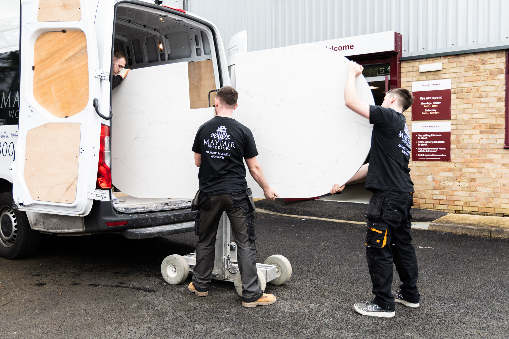 Mayfair Worktops Stonemasons lifting and moving a Volakas White Porcelain slab beside the installation van on site.