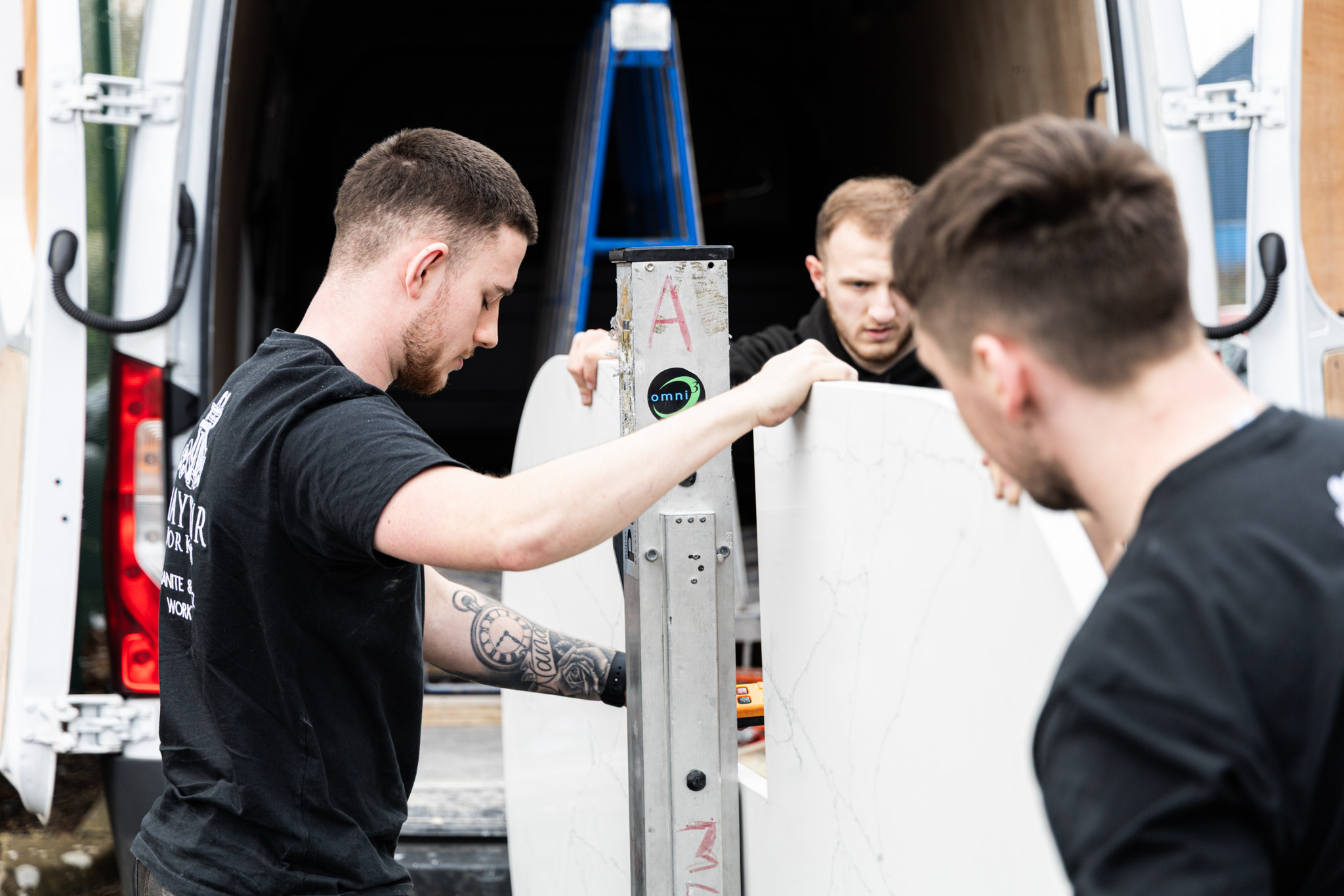 Mayfair Worktops Stonemasons handling a Volakas White Porcelain slab inside the workshop during preparation for installation.