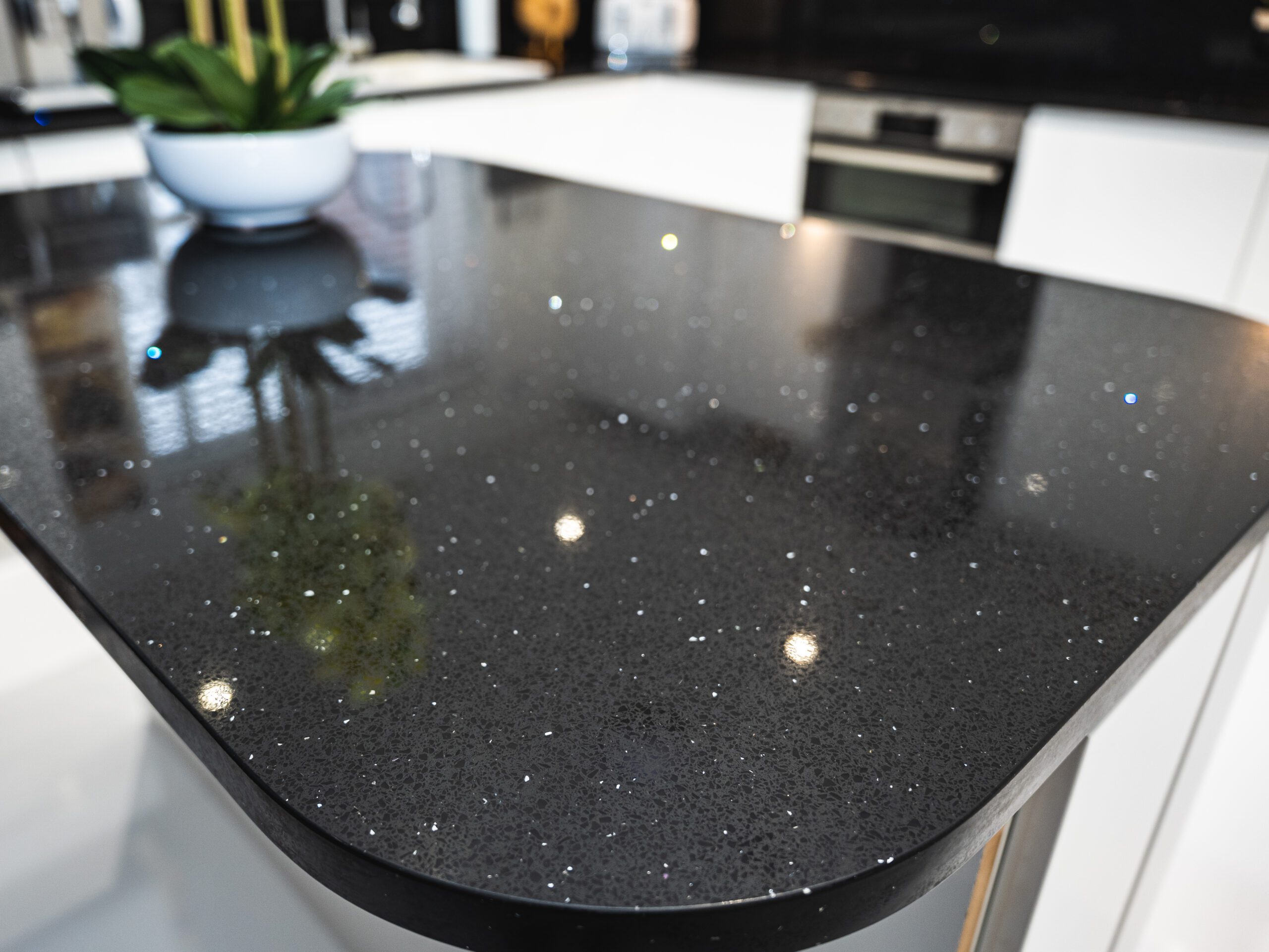 Black Starlight Quartz island worktop close-up showing sparkle flecks and a rounded corner profile