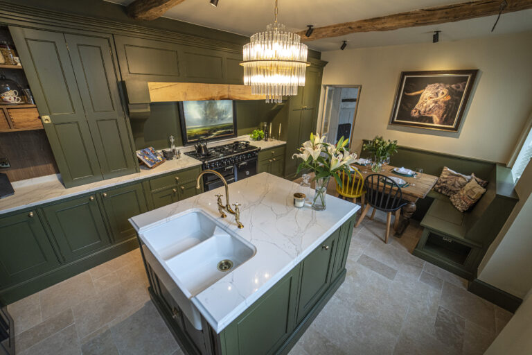 Traditional kitchen with Gold Calacatta island, green cabinetry and chandelier lighting