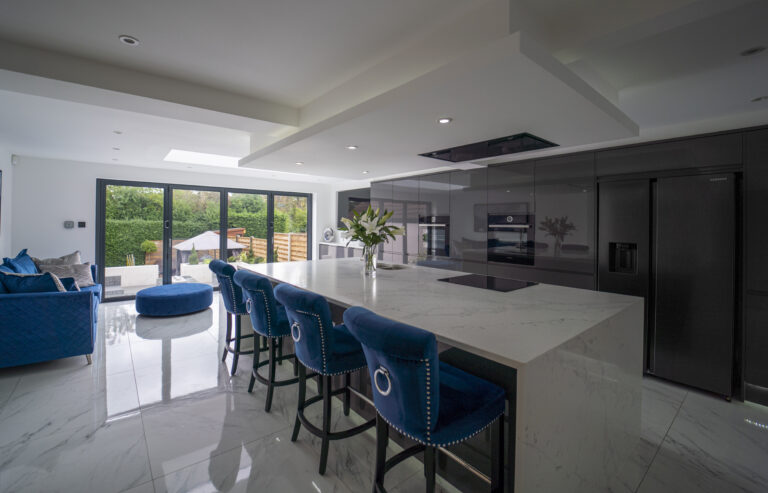 Modern open plan kitchen with White Calacatta Quartz island and blue bar stools under skylights
