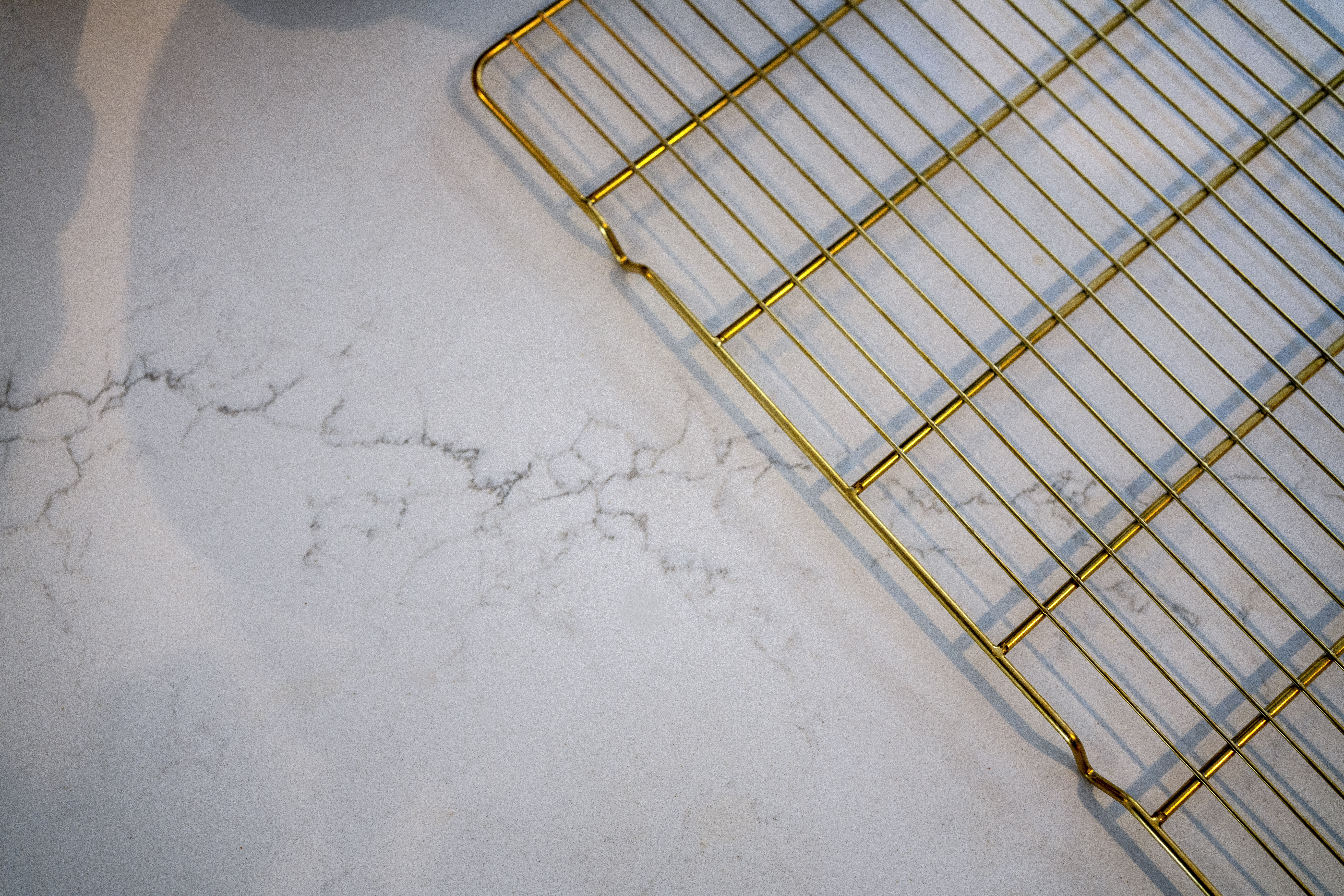 Olympus White Quartz surface close-up showing subtle grey veining beneath a metal cooling rack