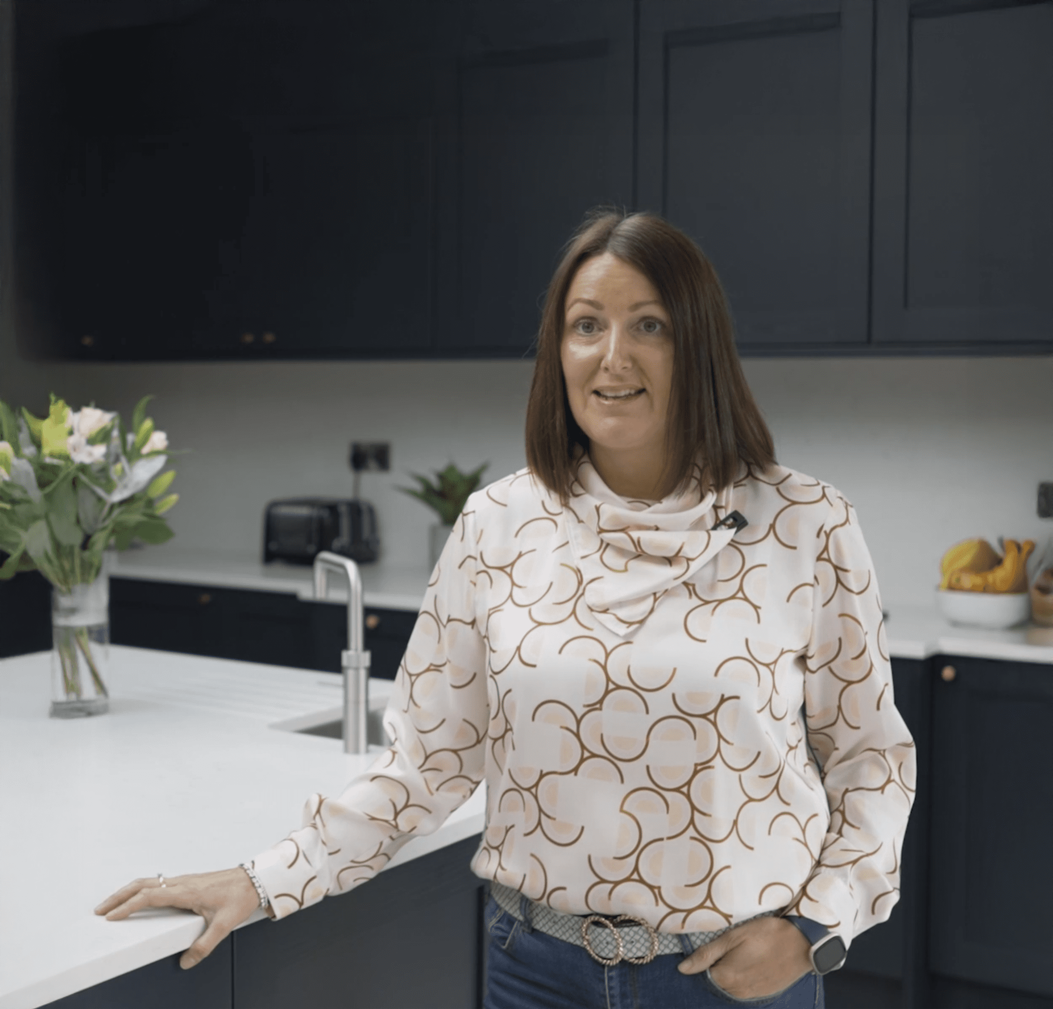 Customer standing in her kitchen with Carrara Quartz worktops installed by Mayfair Worktops