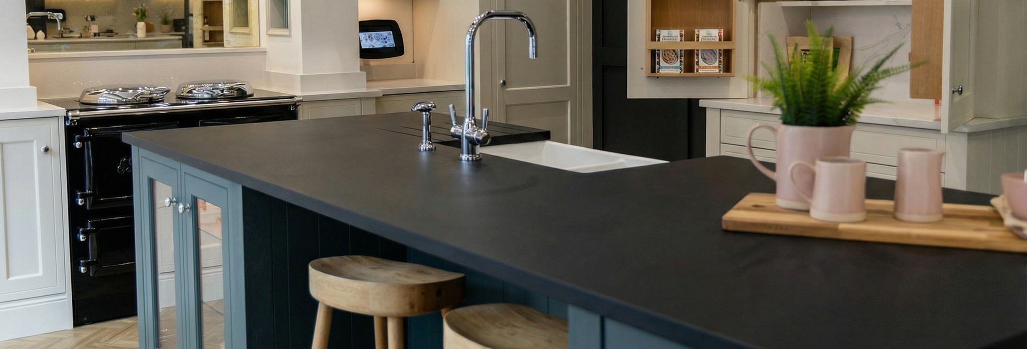 Magma Black Porcelain kitchen island worktop with an inset sink, chrome tap, and wooden bar stools in the background